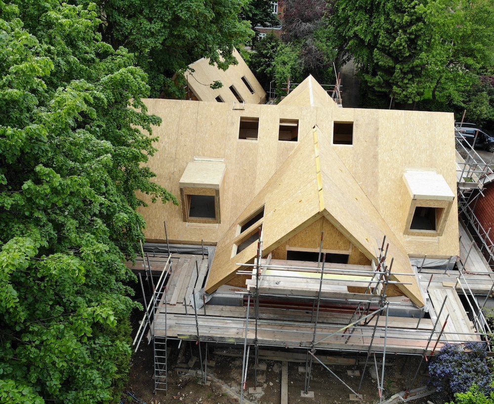 Timber frame structure being erected against a blue sky